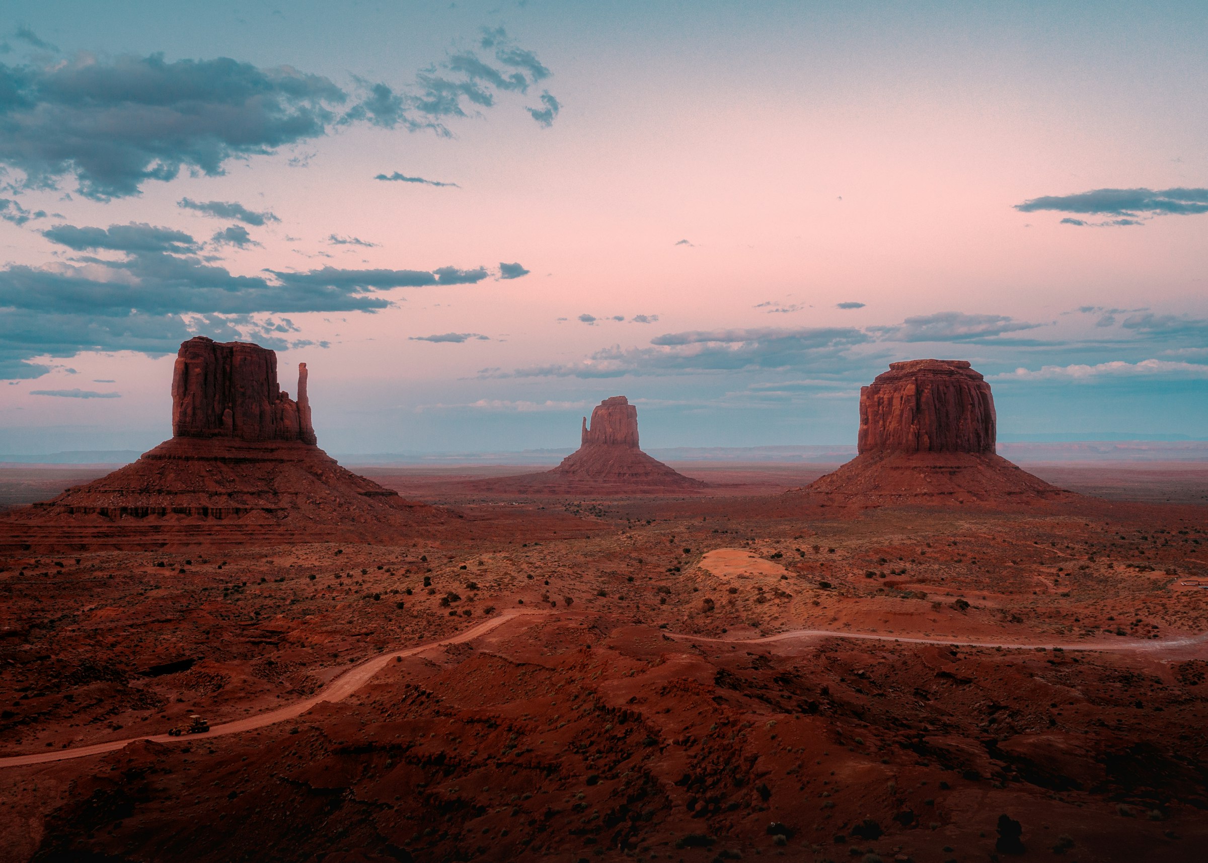Dirt road through the desert toward distant mountains at sunset, Arizona